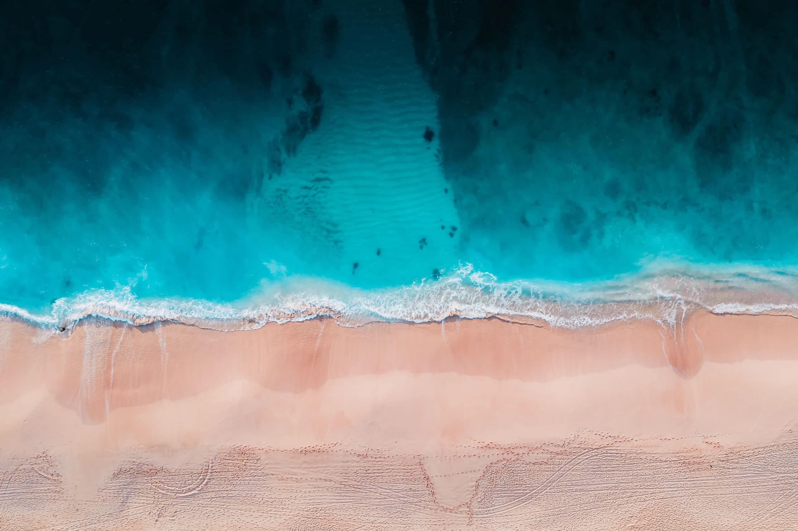 A breathtaking aerial view of a serene turquoise beach with gentle waves lapping the shore.